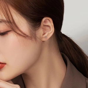 Close-up of minimalist silver spherical stud earring worn on a model's ear cartilage