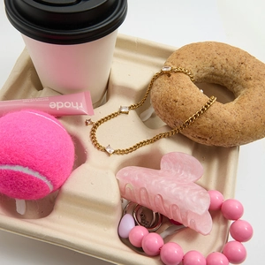 Flatlay of gold zircon necklace and pink marble hair claw clip in a curated tray