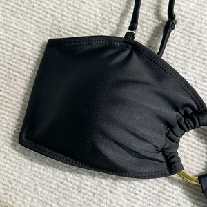 Détail macro du haut de bikini noir avec bretelle réglable et anneau en métal doré