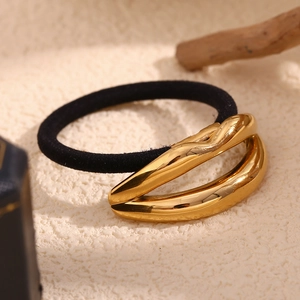 Detailed macro view of an 18K gold plated lip shaped metal hair tie on a white surface