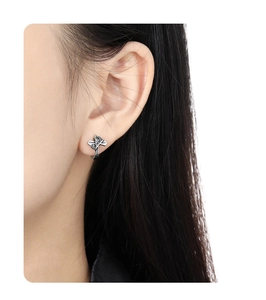 Detail view of retro S925 sterling silver cross crown earring worn on female ear model