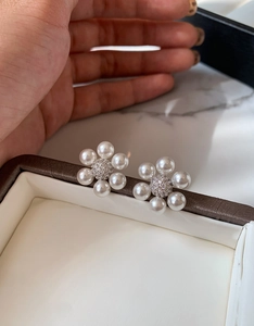 Détail macro de boucles d'oreilles fleurs en perles et zircons sur un écrin à bijoux