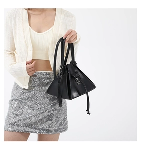 Detail of punk style black triangular bag with silver skull ornament and leather texture