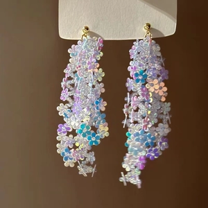 Close-up of iridescent flower sequin tassel earrings with elegant golden metal hooks
