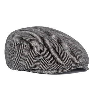 Detailed view of black and white herringbone tweed fabric on a classic flat cap
