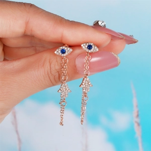 Detail of rose gold Evil Eye and Hamsa Hand chain earrings with blue stones
