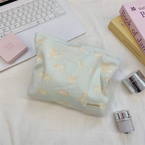 Detailed view of mint green cosmetic bag with orange cat prints and brand woven label