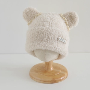 Detail of beige plush earflap hat with cute bear ears and delicate lace trim for girls