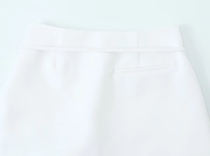 Macro detail of white textured skirt waist featuring belt loops and precise stitching