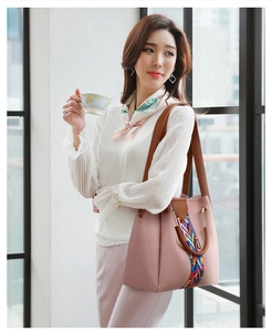 Detail of mauve pink handbag featuring colorful woven ethnic strap and gold ring handle