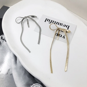 Minimalist metallic bow hair clips in gold and silver finish on a stylish white plate