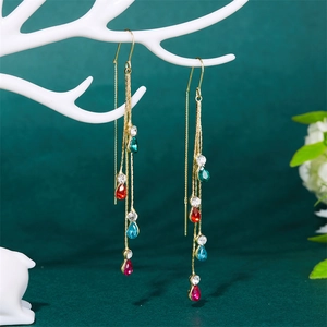 Detail of gold tassel earrings with colorful teardrop crystals on decorative stand