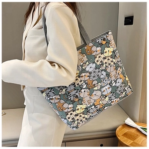 Detail of canvas tote bag with cat print pattern shown on woman in business casual attire