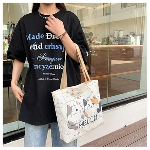 Detail of a beige canvas tote bag with cartoon cat print and durable khaki handles