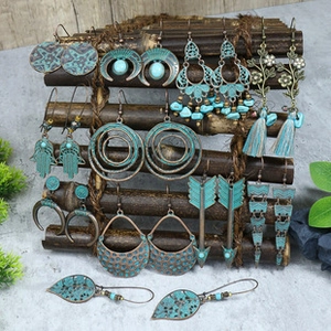 Detail view of Bohemian turquoise earrings featuring Hamsa and moon charms on a bamboo stand