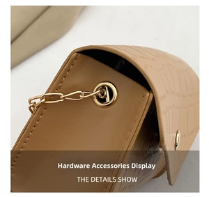 Detailed macro view of golden chain hardware and crocodile embossed tan leather on a handbag