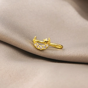 Macro detail of gold moon and star non-pierced nose cuff clip with micro-set zircons