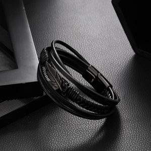 Detailed shot of multi-layer black leather bracelet with feather charm and magnetic clasp