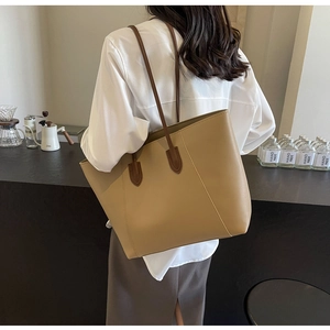 Lifestyle shot of large beige tote bag with brown straps worn on the shoulder in a cafe