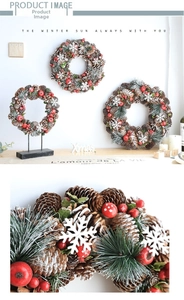 Detail of Christmas wreath featuring natural pine cones, red berries and snowy pine needles