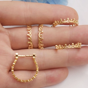 Macro shot of gold-plated crown lace earrings on fingers showing fine details