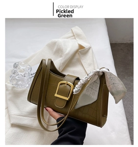 Detail of crocodile-embossed pickle green shoulder bag with gold buckle and silk scarf