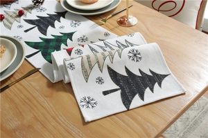 Close-up of modern Christmas table runner with festive tree patterns on a wooden dining table