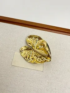 Detail of a vintage golden tulip brooch with intricate leaf texture on beige fabric