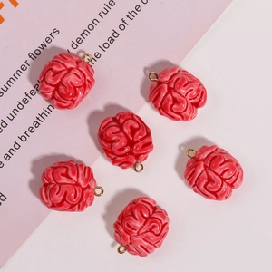 Close-up of six red resin brain pendants with golden metal rings on a pink background