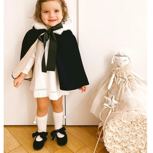 Detail of elegant black velvet baby cape with white faux fur collar and silk bow tie