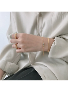 Minimalist gold ring and fine chain bracelet set worn by model for a stylish look