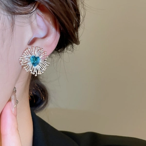 Vue macro d'une boucle d'oreille fleur en argent avec zircon bleu en forme de cœur