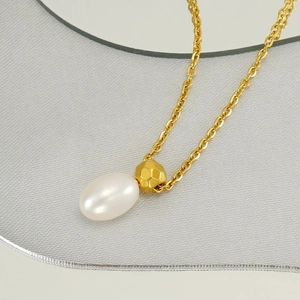 Elegant gold necklace with oval white pearl and geometric gold bead on silk background