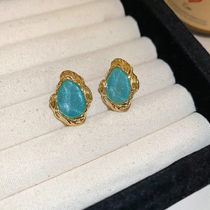 Close-up of vintage blue enamel teardrop earrings with gold textured edges on a jewelry tray