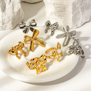 Macro detail of striped bow-knot rings in gold and silver finish with pearls