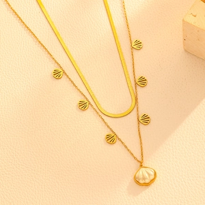Detail of gold double-layered necklace featuring shell pendants and flat snake chain