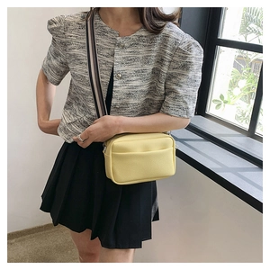 Detail view of yellow lychee leather bag with stylish striped wide shoulder strap