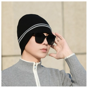 Close-up of black knitted beanie with grey stripes on a model in outdoor setting