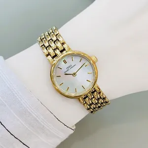 Elegant gold quartz watch with mother of pearl dial and mesh band on woman wrist
