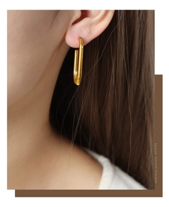Detail of 18K gold plated titanium steel U-shaped earring worn on model's ear