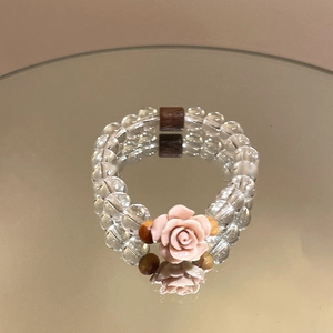 Detailed view of beaded aquamarine bracelet with rose pendant and wooden accents