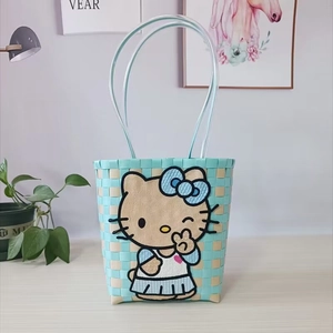 Detailed close-up of sky blue and beige woven handbag featuring large Hello Kitty embroidery