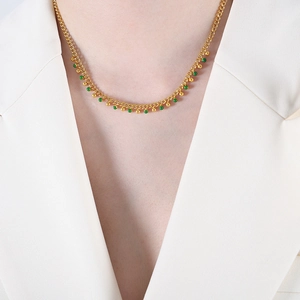 Golden titanium steel tassel necklace with green and gold beads worn on a model
