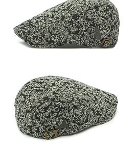 Detail of vintage floral jacquard beret cap with adjustable bronze buckle on white background