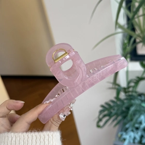 Detailed view of a pink translucent butterfly hair claw clip with golden metal spring