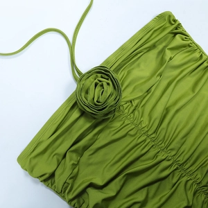 Detail of green ruched dress featuring a 3D fabric rose and chic halter neck straps