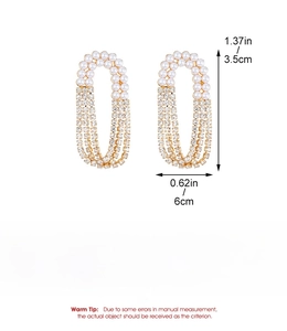 Detail of long heart-shaped earrings with pearls and rhinestone tassels in gold finish