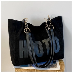 Detail of HOTO embossed letters on black suede tote with metallic chain strap