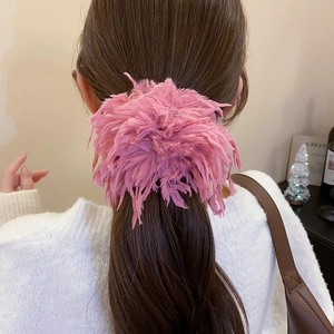 Gros plan d'un chouchou en plumes roses porté sur une queue de cheval pour un look élégant