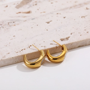 Detail of 18K gold plated C-shaped earrings with sparkling zircon side inlay on stone